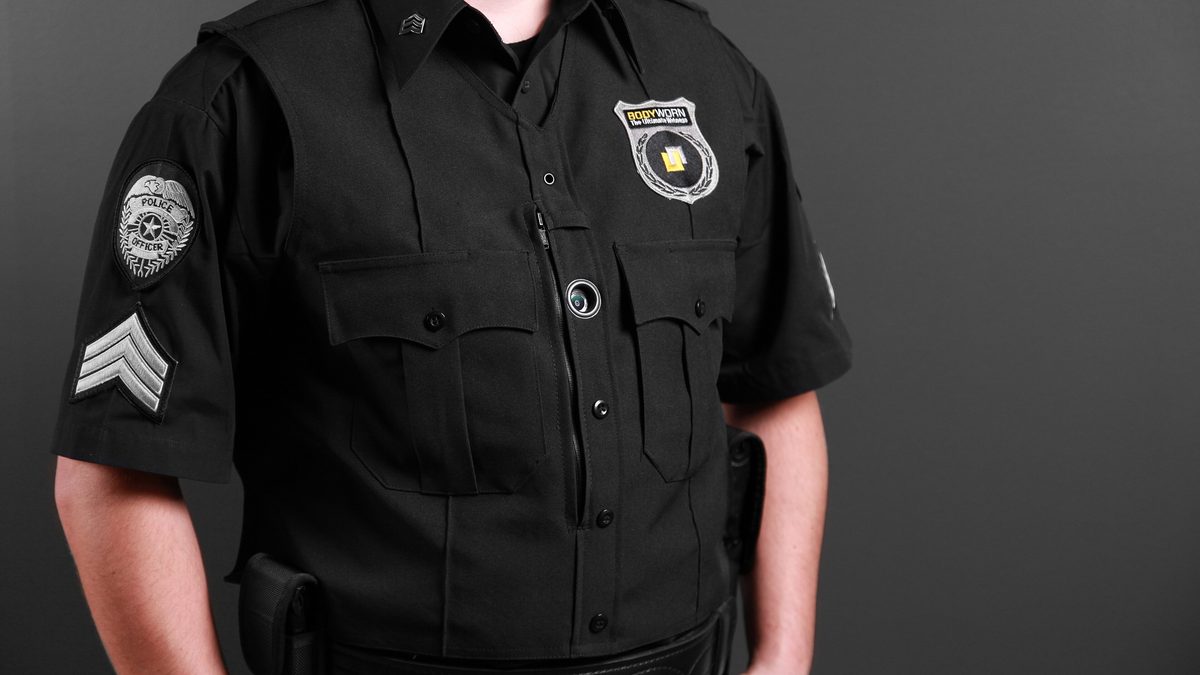 A body camera clipped to the chest of a uniformed officer, whose face is not shown