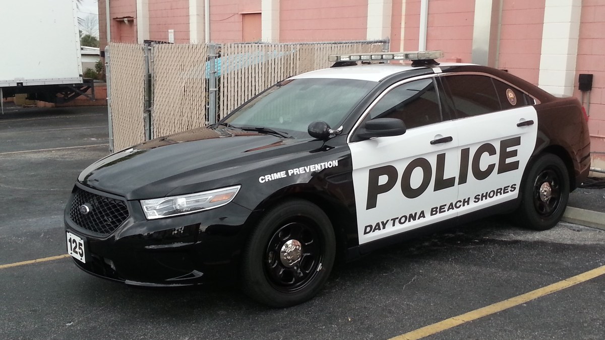 A black and white police car parked outside a building in Daytona Beach Shores, Florida