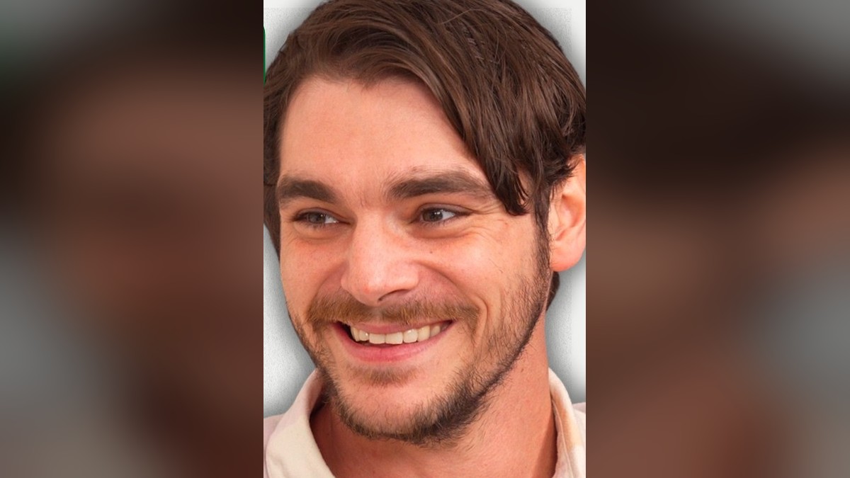 RJ Mitte smiling widely in a light collared shirt