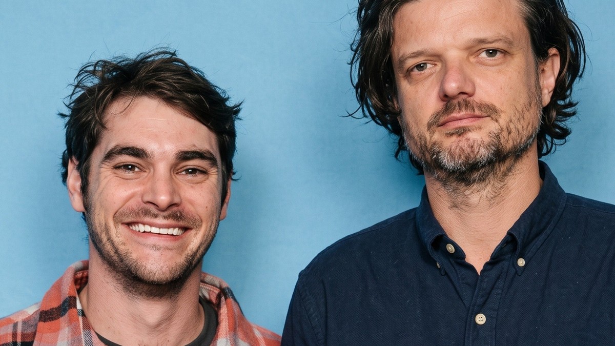Matt Jones and RJ Mitte smiling together against a light blue backdrop