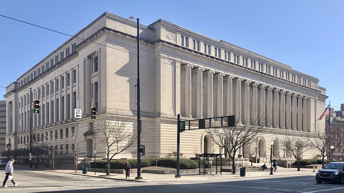 The pale stone Hamilton County Courthouse with its row of tall columns fills a sunny street corner in downtown Cincinnati