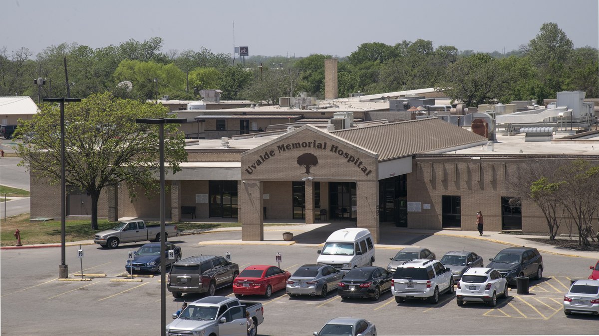 A brick community hospital building with a stone entrance and a parking lot full of cars in Uvalde, Texas