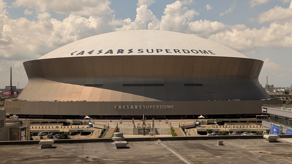 The white dome of the Caesars Superdome, home of the New Orleans Saints, under a sky full of puffy clouds
