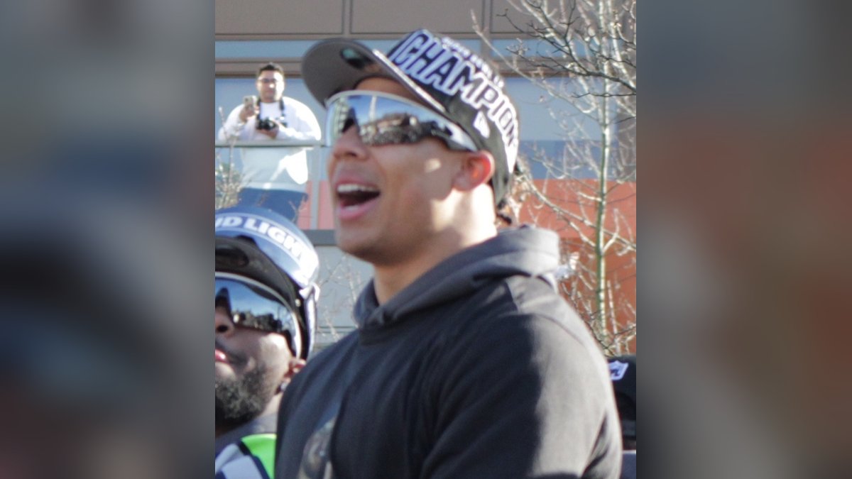 Seattle Seahawks running back Zach Charbonnet cheering in a Super Bowl champions cap and sunglasses at the team's victory parade in Seattle