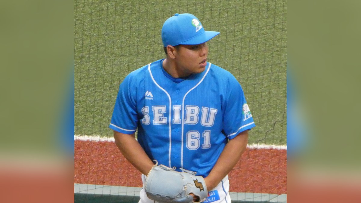 Kaima Taira in a light blue Seibu Lions No. 61 jersey and cap holding his glove near the bullpen