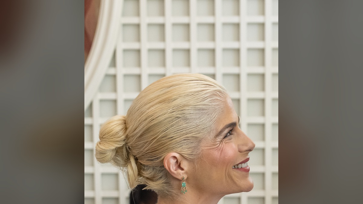 Selma Blair smiling in profile with a green drop earring at the White House
