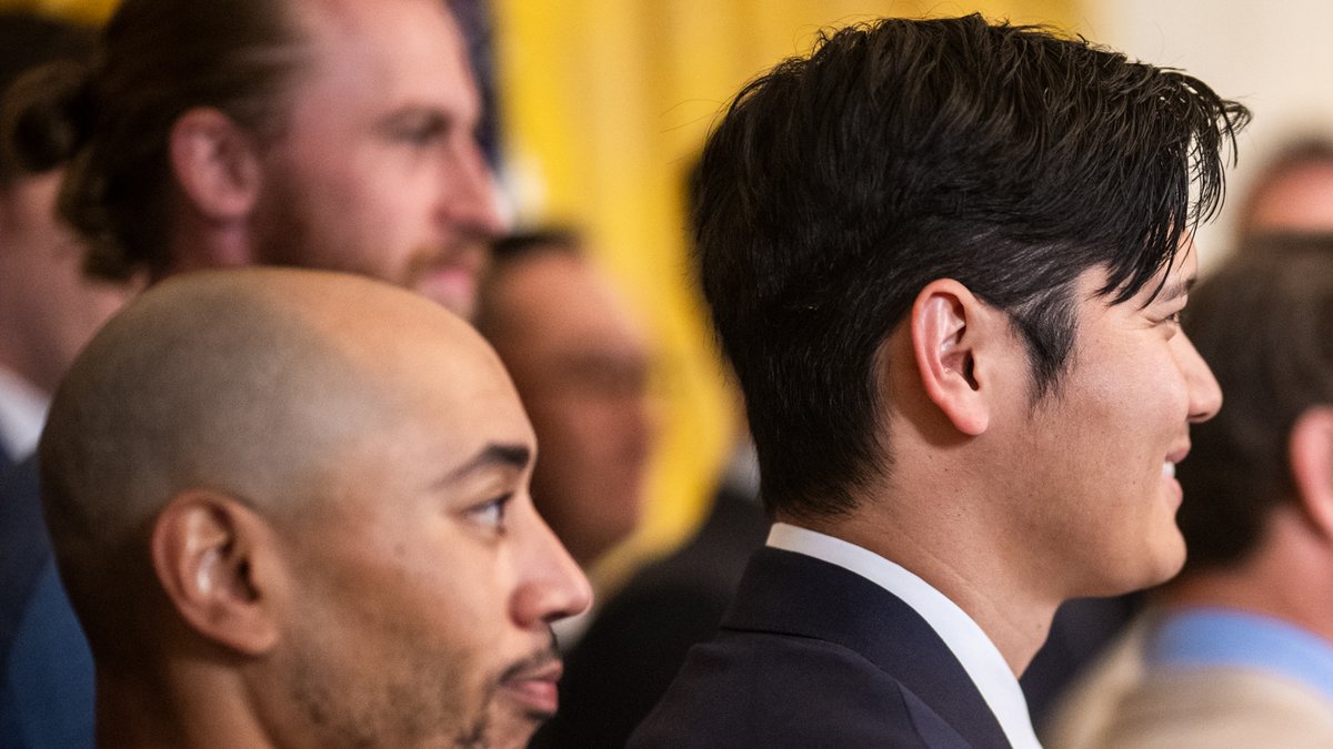 Shohei Ohtani in a dark suit beside teammate Mookie Betts at a Dodgers celebration in Washington