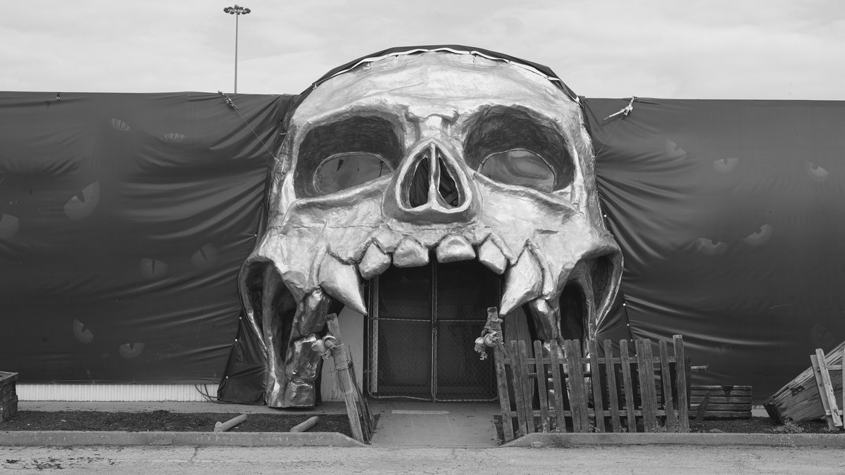 A giant skull-shaped entrance to a Halloween haunted attraction in black and white