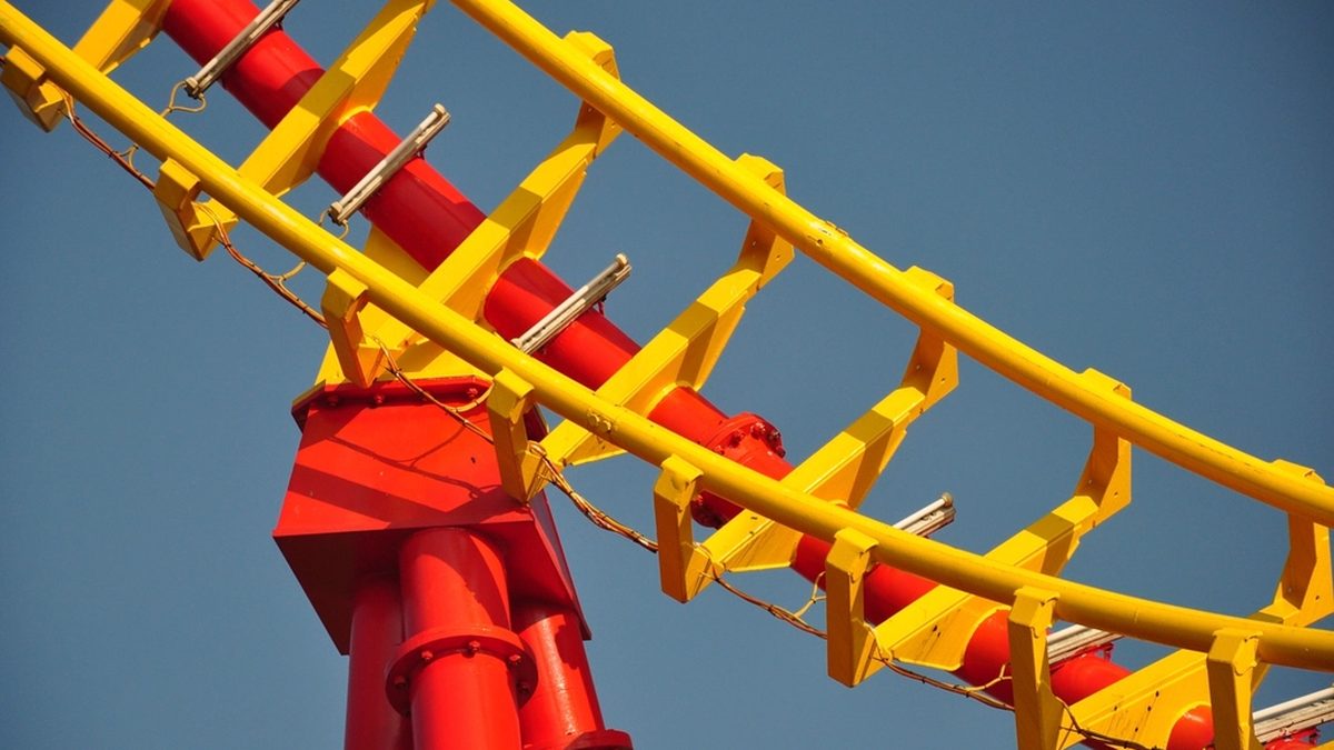 Yellow roller coaster rails on red supports against a clear blue sky
