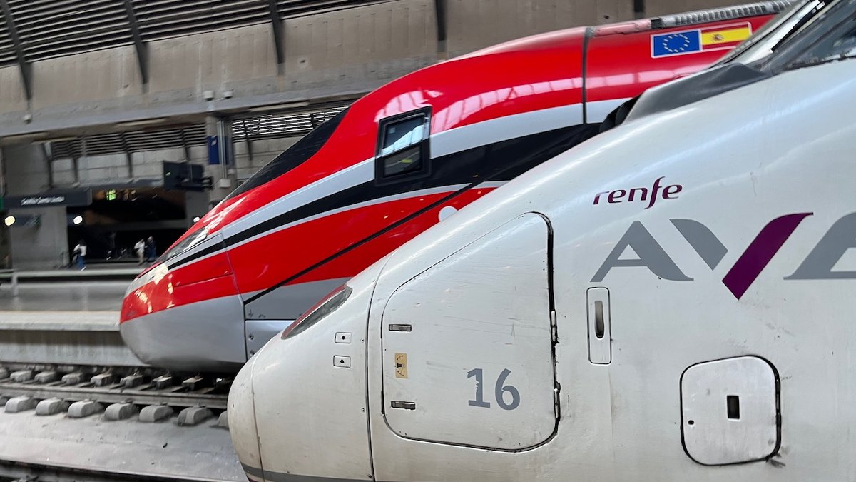 A Renfe AVE train and an Iryo Frecciarossa train side by side at Seville's Santa Justa station