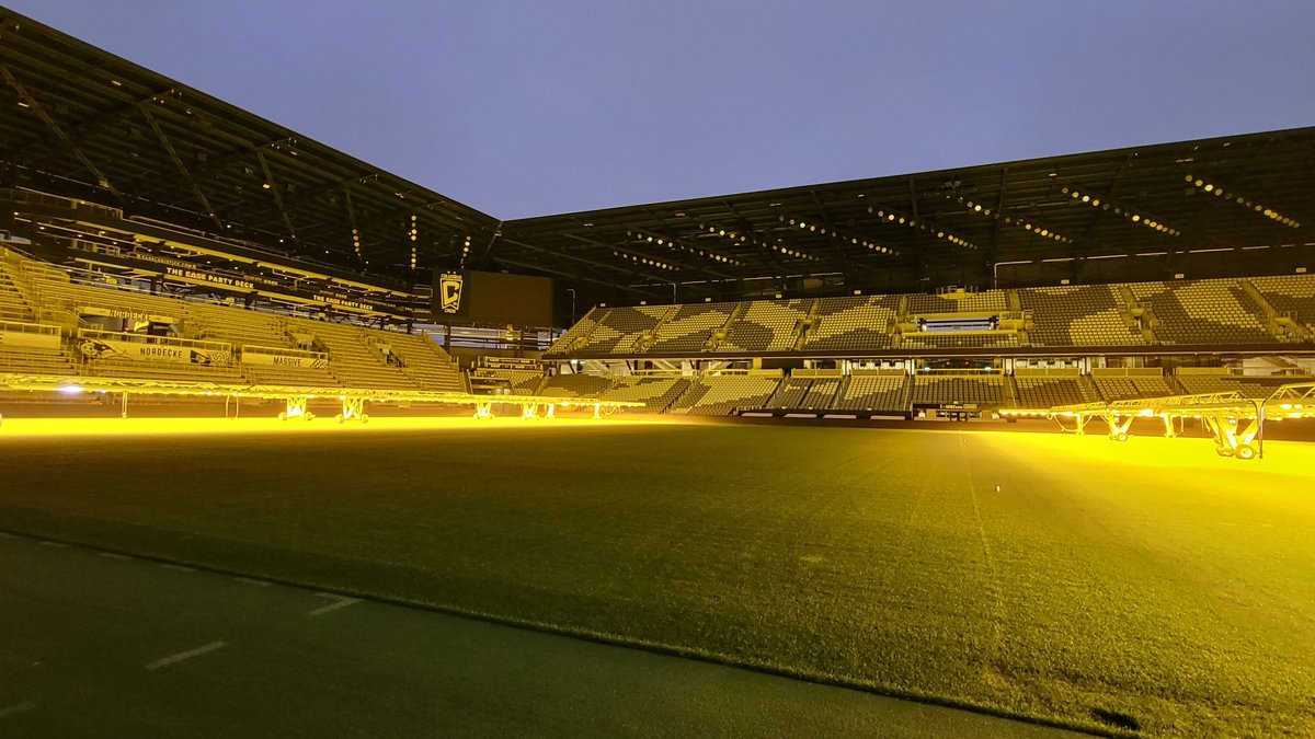 The empty pitch and stands of the Columbus Crew's stadium glowing under grow lights at dusk