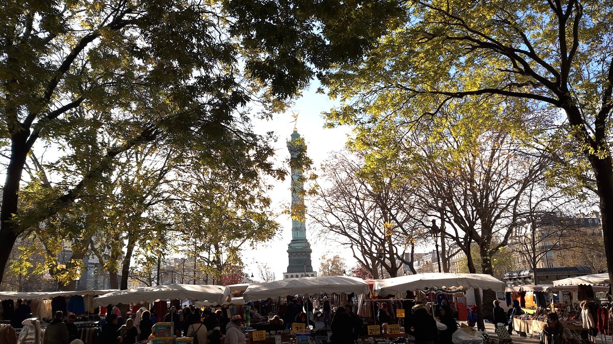 Place de la Bastille in Paris with the July Column rising above market stalls and autumn trees