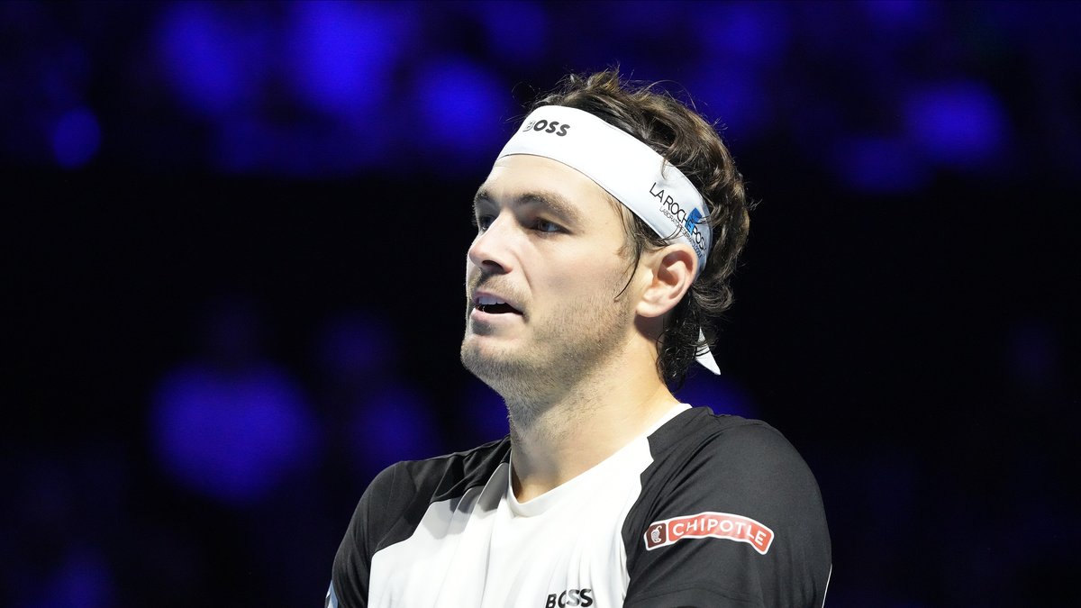 American tennis player Taylor Fritz in a white headband and black and white shirt during an indoor match