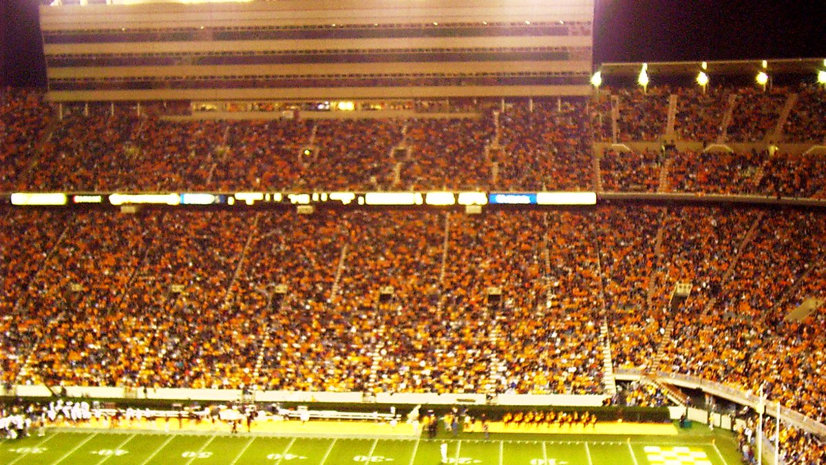 A packed Neyland Stadium glows orange under the lights during a night game in Knoxville