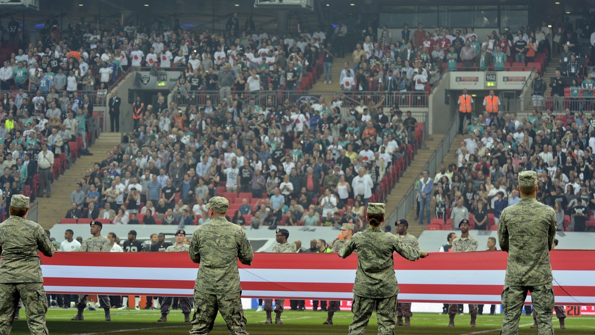 Airmen in camouflage uniforms hold a giant U.S. flag on the field at Wembley Stadium in London before an NFL game in 2014