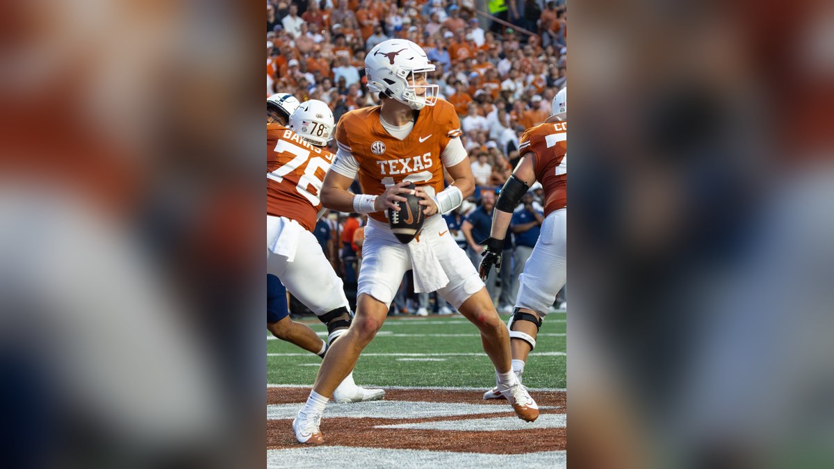 Arch Manning in a burnt orange Texas jersey and white helmet drops back to pass in the end zone at a packed home stadium