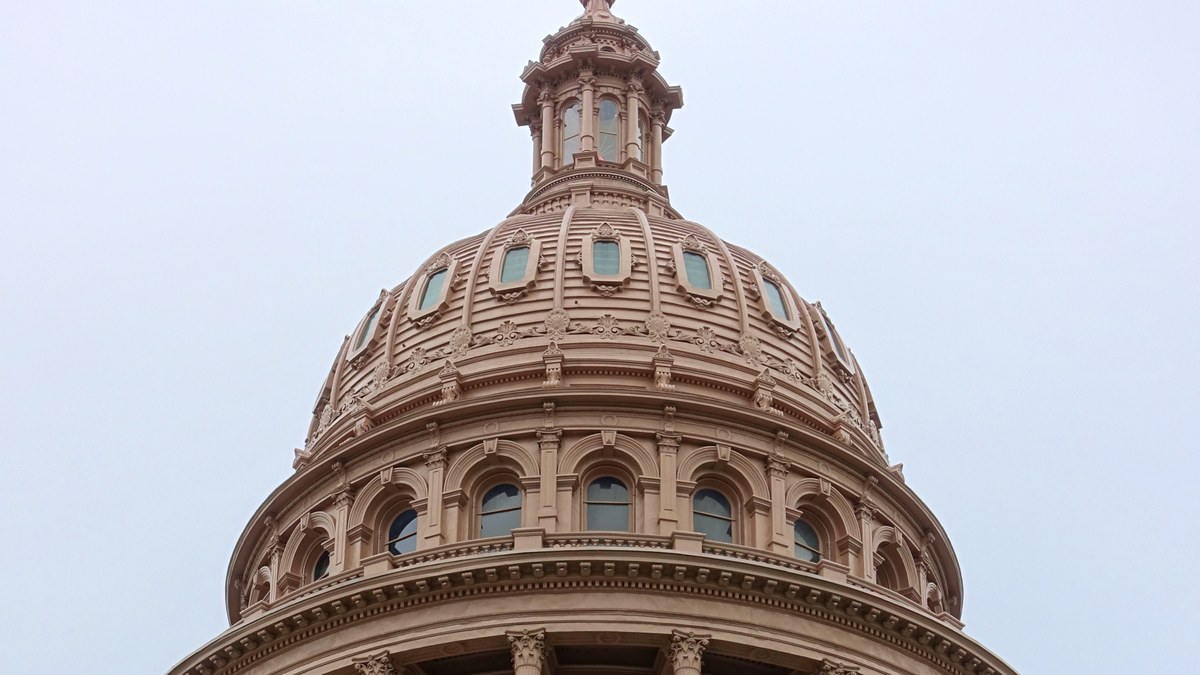 The pink granite dome of the Texas State Capitol in Austin rising against an overcast sky