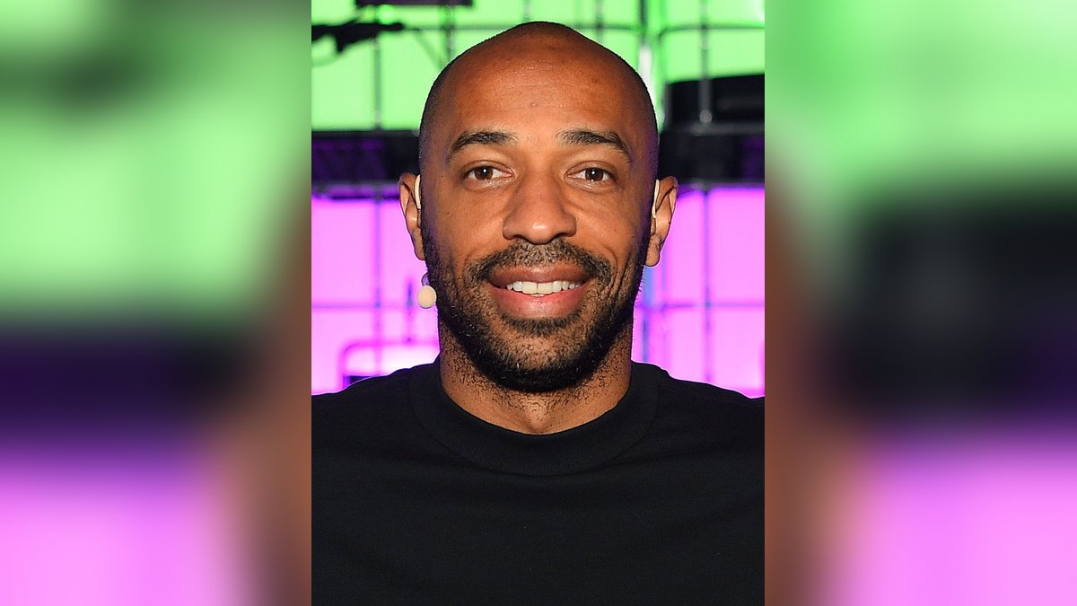 Thierry Henry smiling in a black T-shirt on stage