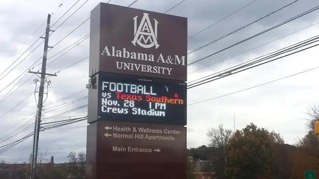 Maroon Alabama A&M University sign with a digital marquee beside a road on the Huntsville campus under a cloudy sky