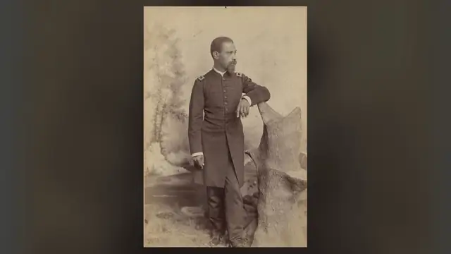 Sepia cabinet-card portrait of Chaplain Allen Allensworth in U.S. Army uniform standing beside a studio prop tree
