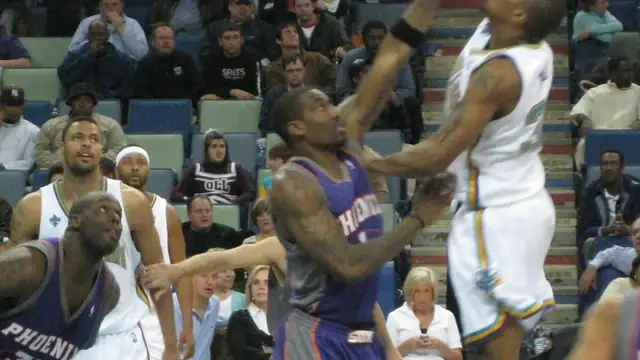 Amar'e Stoudemire in a purple Phoenix Suns jersey fights for position under the basket against the New Orleans Hornets