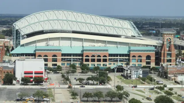 The retractable roof and brick facade of the Houston Astros' ballpark in downtown Houston on a sunny day