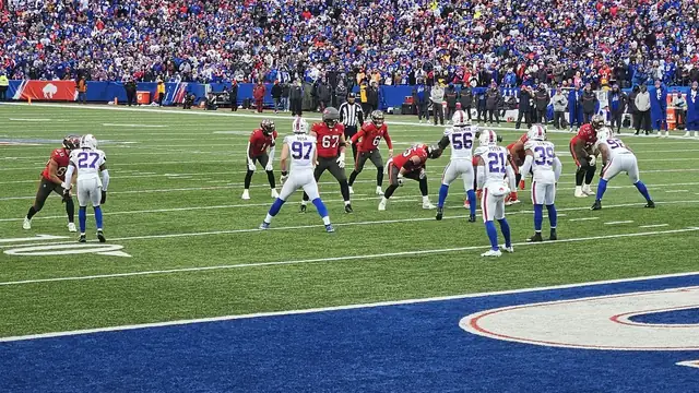 The Tampa Bay Buccaneers offense in red jerseys lines up against the Buffalo Bills defense near the goal line in front of a packed crowd in Orchard Park in 2025