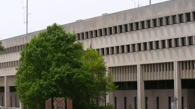 The concrete Baltimore County Courts Building in Towson, Maryland behind a leafy green tree