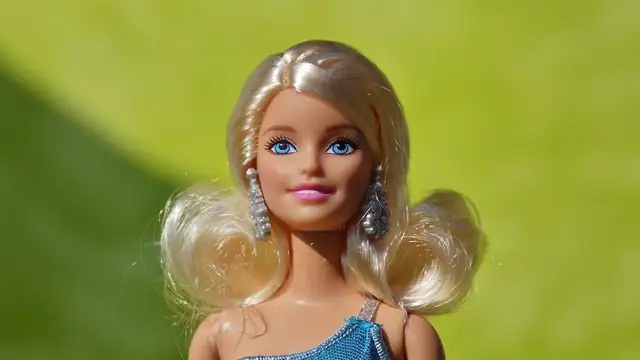 Close view of a blond Barbie doll in a blue top against a green background