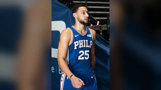 Ben Simmons in a blue Philadelphia 76ers number 25 jersey walks onto the court before a game in 2019