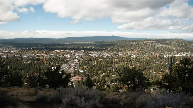 Wide view over the homes and pine trees of Bend, Oregon, from Pilot Butte with mountains on the horizon