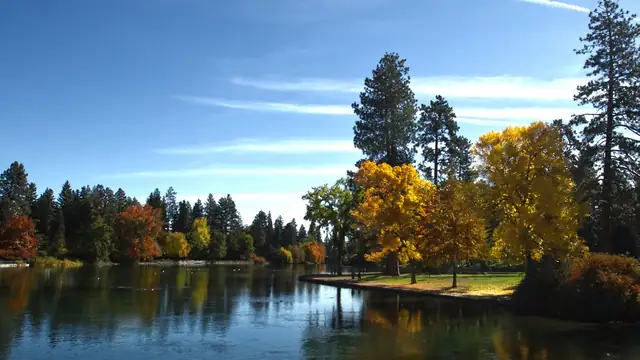Autumn trees in gold and red reflected in the still water of Mirror Pond at Drake Park in Bend, Oregon