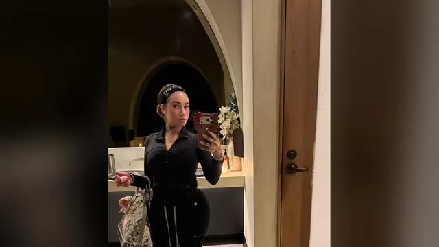 Bhad Bhabie in a black zip-up tracksuit taking a mirror selfie with a designer bag