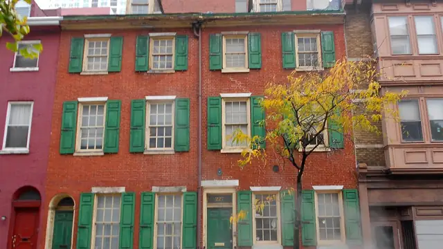 Red brick Philadelphia row houses with green shutters along a city street