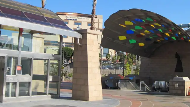 A colorful mosaic canopy arches over the entrance to the Mariachi Plaza transit station in Boyle Heights under a bright blue sky
