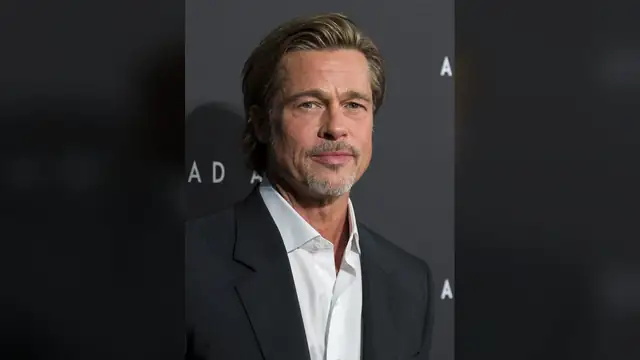 Brad Pitt in a dark suit and white open-collar shirt smiling at a 2019 Ad Astra screening