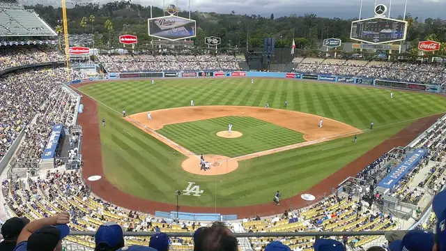 Fans fill the stands above the green field and dirt infield at Dodger Stadium on a cloudy day