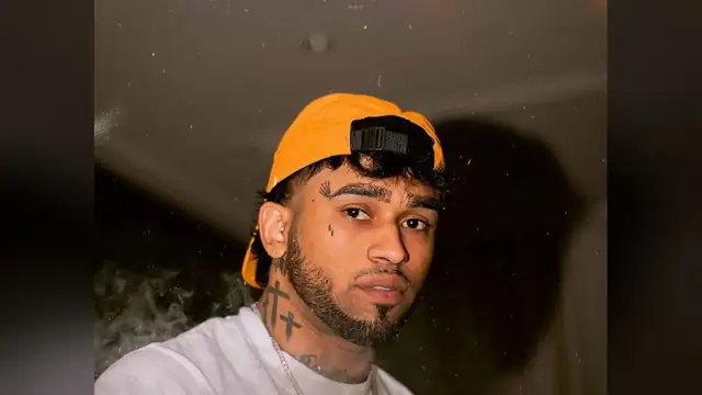Bryant Myers in an orange cap and white T-shirt posing for a photo at night