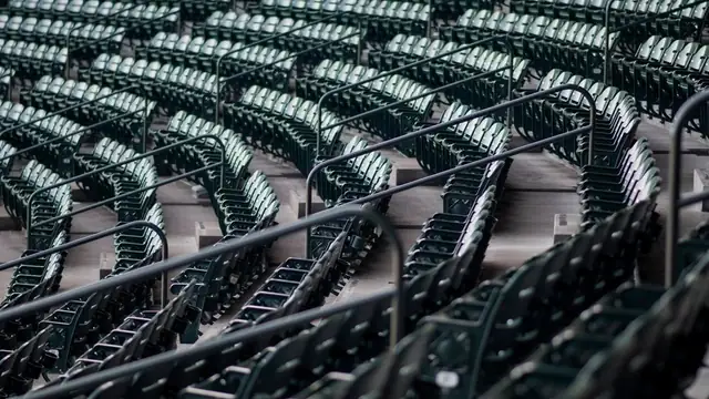 Rows of empty green stadium seats curve around an upper deck
