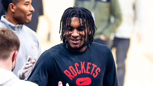 Kevin Porter Jr. smiles in a black Rockets Basketball shirt as he greets a staffer courtside before a game in December 2021