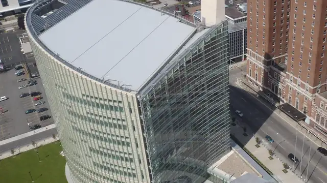 Aerial view of the curved glass Robert H. Jackson U.S. Courthouse in downtown Buffalo beside a tall brick building