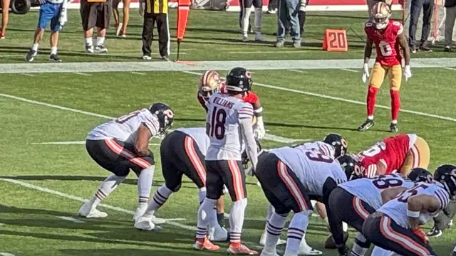 Bears quarterback Caleb Williams in his white No. 18 jersey stands in the shotgun behind his offensive line during a game against the 49ers