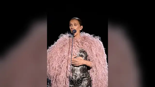 Celine Dion singing on stage in Paris in a pink feathered coat