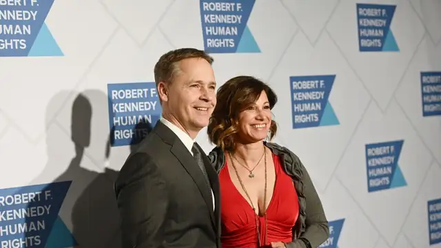 Chad Lowe in a gray suit smiling beside Kim Painter in a red dress at an event