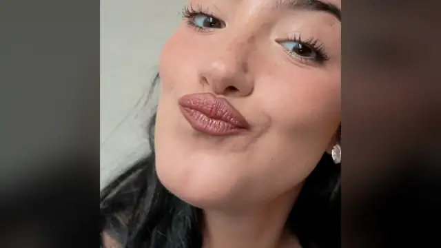 Charli D'Amelio with dark hair pulled back making a playful kissy face