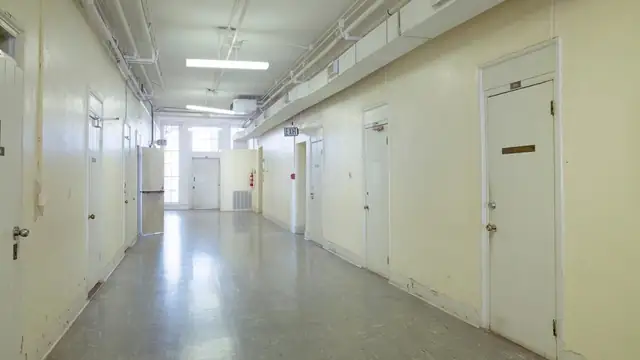 An empty hospital corridor with closed doors and bright overhead lights
