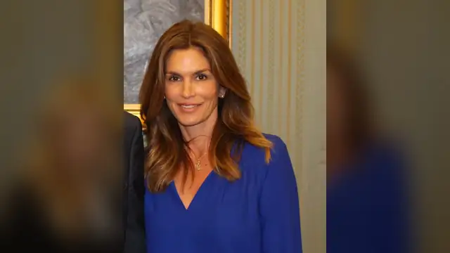 Cindy Crawford smiling in a royal blue blouse at a Senate office