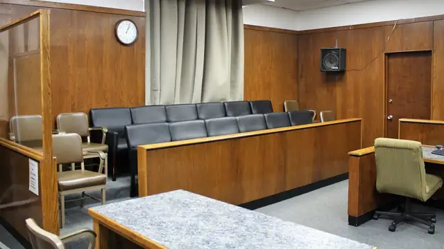 Empty jury box chairs inside a wood-paneled courtroom
