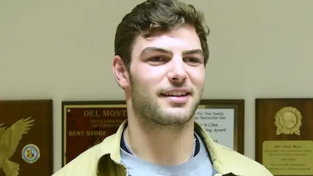 Bears tight end Cole Kmet smiling in a tan jacket during a 2023 visit to a military community