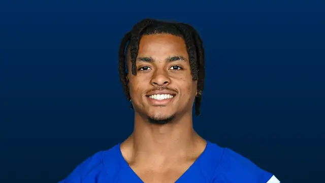 Josh Downs smiling in a blue Indianapolis Colts jersey in a headshot against a dark blue background